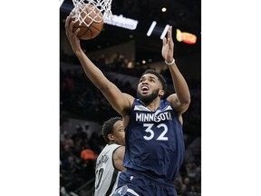 Minnesota Timberwolves' Karl-Anthony Towns (32) shoots as San Antonio Spurs' DeMar DeRozan looks on during the first half of an NBA basketball game, Friday, Dec. 21, 2018, in San Antonio.