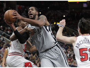 San Antonio Spurs forward LaMarcus Aldridge (12) drives to the basket between Chicago Bulls defenders Wendell Carter Jr., left, and Ryan Arcidiacono, right, during the first half of an NBA basketball game, Saturday, Dec. 15, 2018, in San Antonio.