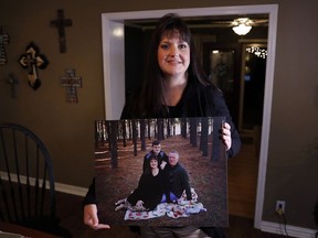 In this Thursday, Dec. 20, 2018 photo, Reagen Adair poses for a photo at her home holding a portrait of herself, with her husband Dale and son Mason, in Murchison, Texas. Adair, a fifth-grade teacher, had $3,100 in debt erased by RIP Medical Debt. The co-founders of RIP buy millions of dollars in past-due medical debt for pennies on the dollar.