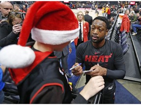 Miami Heat guard Dwyane Wade signs an autograph for a young fan before the start of their NBA basketball game against the Utah Jazz Wednesday Dec. 12, 2018, in Salt Lake City.