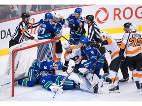 Vancouver Canucks goalie Jacob Markstrom (25), of Sweden, covers up the puck as Troy Stecher (51) kneels in the net while Ben Hutton (27) and Nikolay Goldobin (77), of Russia, hold back Philadelphia Flyers' Jori Lehtera (15), of Finland, as Shayne Gostisbehere (53) gets into a scuffle with Vancouver's Jake Virtanen (18) during the second period of an NHL hockey game in Vancouver, on Saturday December 15, 2018.