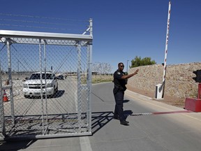 FILE - In this June 21, 2018, file photo, an agent with the Department of Homeland Security controls access to a holding facility for immigrant children in Tornillo, Texas. The Trump administration is reversing a policy that required fingerprinting for all adults living in a household where a migrant child would live. Parents and other sponsors have said the fingerprinting rule had slowed placement of children in homes, in part because some members of the household were afraid to be fingerprinted.