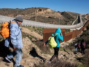 A group of Central American migrants look for a spot to cross the US-Mexico border fence from Tijuana, Baja California State, Mexico, into the US, on December 30, 2018. - Outgoing White House chief John Kelly said he had "nothing but compassion" for undocumented migrants crossing into the US and undercut the idea of a border wall in an interview published Sunday that jarred with President Donald Trump's rhetoric on immigration.