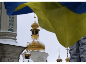 A Ukrainian national flag flutters in the wind as people gather to support independent Ukrainian church near the St. Sophia Cathedral in Kiev, Ukraine, Saturday, Dec. 15, 2018.  Ukraine's Orthodox clerics gather for a meeting Saturday that is expected to form a new, independent Ukrainian church, and Ukrainian authorities have ramped up pressure on priests to support the move.