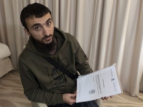 In this photo taken on Wednesday, Nov. 14, 2018, Tumso Abdurakhmanov, the 32-year-old Chechen video blogger, holds a letter from Interpol during an interview with The Associated Press somewhere in Poland. Abdurakhmanov, a critic of the Chechen ruler, faces deportation from Poland as European nations become increasingly wary of sheltering refugees from Chechnya.