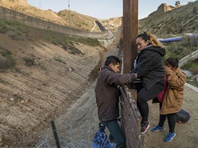 A pregnant migrant climbs the border fence before jumping into the U.S. to San Diego, Calif., from Tijuana, Mexico, Thursday, Dec. 27, 2018. Discouraged by the long wait to apply for asylum through official ports of entry, many Central American migrants from recent caravans are choosing to cross the U.S. border wall and hand themselves into border patrol agents.