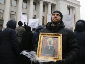 Believers of the Ukrainian Orthodox Church of Moscow Patriarchy protest against the creation of a Ukrainian independent church, in front of the parliament building in Kiev, Ukraine, Thursday, Dec. 20, 2018. Writing on the poster reads "We pray God to give you mind."