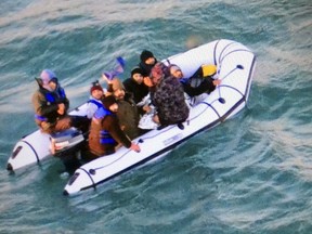 This image provided by the Marine Nationale (French Navy) shows migrants aboard a rubber boat after being intercepted by French authorities, off the port of Calais, northern France, Tuesday, Dec. 25, 2018. French authorities have rescued eight migrants, including two children, whose engine failed as they tried to sneak across the English Channel to Britain.