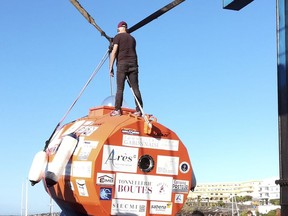 In this photograph taken Saturday Dec. 22, 2018, Frenchman Jean-Jacques Savin, 71-year-old, stands on top of his 3-metre (10-foot) long, 2.1-metre (7-foot) wide resin-coated plywood capsule, which will use ocean currents alone to propel him across the sea. Savin set off from El Hierro in Spain's Canary Islands on Wednesday and is aiming to complete his 4,500-kilometre (2,800-mile) journey to the Caribbean in about three months. (Courtesy of Jean-Jacques Savin via AP)