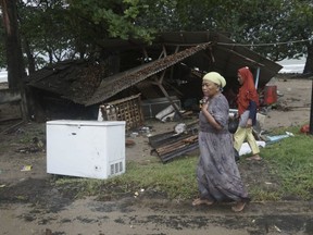Residents walk past a house damaged by a tsunami, in Carita, Indonesia, Sunday, Dec. 23, 2018. The tsunami apparently caused by the eruption of an island volcano killed a number of people around Indonesia's Sunda Strait, sending a wall of water crashing some 65 feet (20 meters) inland and sweeping away hundreds of houses including hotels, the government and witnesses said.