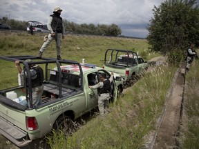 FILE - In this July 11, 2017 file photo, Pemex security employees inspect an illegal tap into a state-owned pipeline in the middle of a cornfield in San Bartolome Hueyapan, Tepeaca, Mexico. The theft of $3 billion in fuel every year from Mexico's state-run fuel depots and pipelines is an inside job, the country's new president said Thursday, dec. 27, 2018.