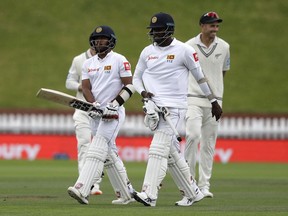 Sri Lankan batsmen Kusal Mendis, left, and teammate Angelo Mathews walk from the field as rain stops play during play on the final day of the first cricket test between New Zealand and Sri Lanka in Wellington, New Zealand, Wednesday, Dec. 19, 2018.