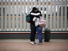 Migrants embraces after receiving one of the fifty turns for an interview to request U.S. asylum, alongside the El Chaparral pedestrian border crossing in Tijuana, Mexico, Friday, Dec. 21, 2018.