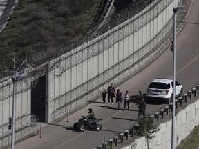 Honduran asylum seekers are taken into custody by U.S. Border Patrol agents after the group crossed the U.S. border wall into San Diego, California, seen from Tijuana, Mexico, Sunday, Dec. 16, 2018.