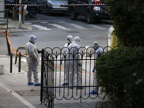 Greek forensic experts search at the scene after an explosion outside the Orthodox church of Agios Dionysios in the upscale Kolonaki area of Athens, Thursday, Dec. 27, 2018. Police in Greece say an officer has been injured in a small explosion outside a church in central Athens while responding to a call to investigate a suspicious package.