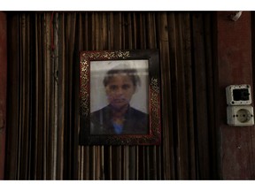 In this Oct. 21, 2018, photo, a framed photo of Adelina Sau hangs on the wall of her family's home in Abi village in West Timor, Indonesia. Adelina had been working as a maid for a Malaysian family when a local lawmaker's office received a tip from neighbors who suspected she was being abused. Following her death, an autopsy determined she died of septicemia and cited possible abuse and neglect.