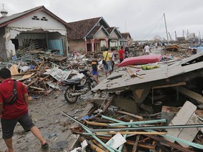 People inspect the damage at a tsunami-ravaged village in Sumur, Indonesia, Tuesday, Dec. 25, 2018. The Christmas holiday was somber with prayers for tsunami victims in the Indonesian region hit by waves that struck without warning Saturday night.