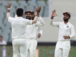 India's Virat Kohli, second left, congratulates teammate Jasprit Bumrah, left, after taking the wicket of Australia's Mitchell Starc during the first cricket test between Australia and India in Adelaide, Australia,Saturday, Dec. 8, 2018.