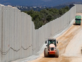 A file photo taken on September 05, 2018 near the Rosh Hanikra border crossing in northern Israel, shows tractors along a new wall on the Israeli-Lebanese border.