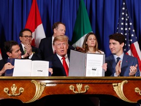 Justin Trudeau half-heartedly applauds but does not show off his signing of the USMCA documents. Foreign Affairs Minister Chrystia Freeland behind him tries to will him to raise the document, while U.S. Trade Representative Robert Lighthizer is a little more pointed about the refusal.