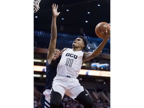 Grand Canyon's Carlos Johnson (11) drives to the basket against Nevada's Tre'Shawn Thurman (0) during the first half of an NCAA college basketball game Sunday, Dec. 9, 2018, in Phoenix.