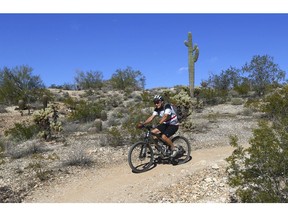 A mountain biker heads south along the Maricopa Trail inside the White Tank Mountain Regional Park Wednesday, Nov. 28, 2018, in Waddell, Ariz.  Maricopa County has completed a 315-mile (507-kilometer) hiking and biking trail that circles Phoenix and most of its suburbs.