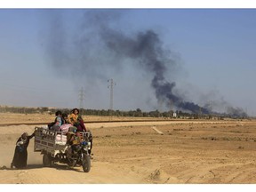 FILE - In this Monday, April 4, 2016 file photo, smoke rises as people flee their homes during clashes between Iraqi security forces and members of the Islamic State group in Hit, Iraq, 85 miles (140 kilometers) west of Baghdad, Iraq.Iraq on Monday, Dec. 10, 2018 celebrated the anniversary of its costly victory over the Islamic State group, which has lost virtually all the territory it once held but still carries out sporadic attacks.