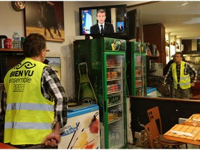 Yohann Piedagnel watches French President Emmanuel Macron during a televised address to the nation, in Hendaye, southwestern France, Monday, Dec. 10, 2018.  In an unusual admission, French President Emmanuel Macron says he's partially responsible for anger fueling protests.