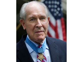 FILE - In this July 12, 2013, file photo, retired U.S. Navy Capt. Thomas Hudner wears the Medal of Honor awarded to him by President Truman, as he poses on the porch at his home in Concord, Mass. Hudner intentionally crashed his plane during the Korean War in 1950 to try to save his wingman Jesse Brown, whose plane had been shot down. A U.S. Navy destroyer named in Hudner's honor will be commissioned Saturday, Dec. 1, 2018, in Boston. He died, Nov. 13, 2017, at age 93.