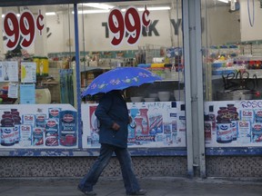 A pedestrian walks past a 99-Cents store under light rain in Los Angeles Wednesday, Dec. 5, 2018. A fall storm is causing slick conditions on Southern California freeways but isn't expected to generate enough rain to trigger mudslides or debris flows on hillsides charred by recent fires.