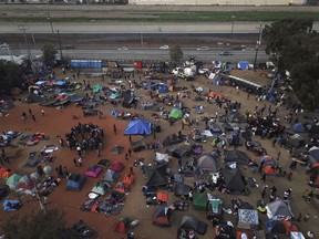 FILE - In this Wednesday, Nov. 21, 2018 file photo, Central American migrants gather at a temporary shelter, near barriers that separate Mexico and the United States, in Tijuana, Mexico. A Honduran woman affiliated with a caravan of Central American migrants gave birth on U.S. soil shortly after entering the country illegally amid growing frustration about a bottleneck to claim asylum at official border crossings. Border Patrol agents arrested the woman Nov. 26 after she entered the country illegally near Imperial Beach, Calif., across the border from Tijuana, Mexico, Customs and Border Protection said Wednesday, Dec. 5, 2018.