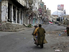 FILE - In this Feb. 4, 2018, file photo, men ride through streets wrecked by fighting in Taiz, Yemen in this Feb. 4, 2018, photo. Envoys from Yemen's warring parties are headed to Sweden for another round of peace talks to stop the three-year-old war, but with few incentives to compromise, expectations are low for little more than improving a faltering de-escalation.