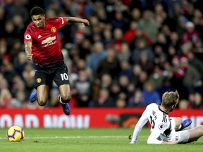 Manchester United's Marcus Rashford, left, jumps over a challenge from Fulham's Tim Ream, right, during the English Premier League soccer match between Manchester United and Fulham, at Old Trafford, Manchester, England, Saturday, Dec. 8, 2018.