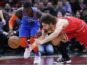 Oklahoma City Thunder guard Dennis Schroeder, left, and Chicago Bulls center Robin Lopez vie for a loose ball during the first half of an NBA basketball game Friday, Dec. 7, 2018, in Chicago.