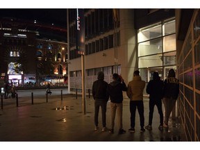 In this Nov. 9, 2018 photo, unaccompanied minors from Morocco seeking shelter, stand outside a police station in Barcelona, Spain. Slouched on a bench at a Barcelona police station, five teenagers waited patiently on a recent Friday evening to find out where they would sleep that night: a shelter for young migrants or on that bench.