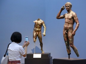 In this Monday, July 27, 2015 photo, reporter Sookee Chung takes a photo of a sculpture titled "Statue of a Victorious Youth, 300-100 B.C." at the J. Paul Getty Museum in Los Angeles. The J. Paul Getty Museum in Los Angeles has vowed to assert its right to keep an important Greek statue after Italy's highest court rejected its appeal of a ruling ordering the artwork to be returned to Italy. The ANSA news agency said Tuesday that the Court of Cassation rejected the appeal outright earlier this week. "Victorious Youth," a nearly life-sized bronze dating from 300 B.C. to 100 B.C., is one of the highlights of the Getty collection.