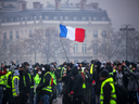 Demonstrators gather under a French flag near the Arc de Triomphe during a protest of 