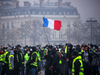 Demonstrators gather under a French flag near the Arc de Triomphe during a protest of “gilets jaunes” (yellow vests) against rising oil prices and living costs, Dec. 1, 2018 in Paris.