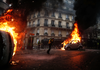 Protesters walk by burning cars during clashes with riot police on the sideline of a protest of “gilets jaunes” (yellow vests) against rising oil prices and living costs, on Dec. 1, 2018 in Paris.