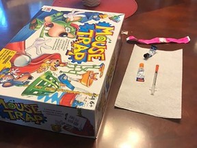 A board game, syringe and glue are seen in this undated handout photo. A father in Pitt Meadows, B.C., says the last thing his family expected to find inside a second-hand board game was a syringe and toxic glue.