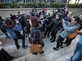 Members of the media crowd around an unidentified woman who was attending a bail hearing for Meng Wanzhou, the chief financial officer of Huawei Technologies, during a break in proceedings at B.C. Supreme Court in Vancouver, on Friday December 7, 2018.