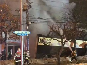 In this image taken from mobile phone video, emergency workers attend the scene after an explosion at a two-storey Japanese restaurant in Sapporo, the capital city of Japan's northern main island, Sunday Dec. 16, 2018.  More than 40 people were injured in the explosion Sunday night, and authorities are investigating the cause of the blast.