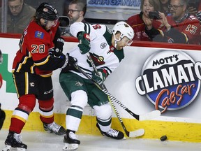 Minnesota Wild's Jason Zucker, right, is checked by Calgary Flames' Elias Lindholm, of Sweden, during second period NHL hockey action in Calgary, Thursday, Dec. 6, 2018.