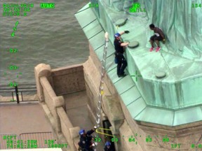 In this July 4, 2018, file photo from video provided by the New York City Police Department, members of the NYPD Emergency Service Unit work to safely remove Therese Okoumou, who climbed onto the Statue of Liberty to protest the border separation of children. Okoumou was convicted of misdemeanor charges on Monday, Jan. 17,