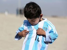 FILE - In this Friday, Feb. 26, 2016 file photo, five-year-old Afghan Lionel Messi fan Murtaza Ahmadi poses for photograph, as he wears a shirt signed by Messi, in Kabul, Afghanistan. A young Afghan soccer fan who shot to fame after he was photographed in a Messi shirt made from a plastic bag has been forced to flee with his family to the Afghan capital after criminal gangs and the Taliban threatened to kill or kidnap him. Shafiqa Ahmedi said Friday, Dec. 7, 2018 that criminals threatened to kidnap her now-7-year-old son Murtaza, a fan of Argentinian soccer star Lionel Messi, after demanding money.