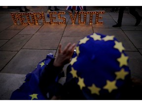 The lit up words "Peoples Vote", which calls for another referendum on Britain's European Union membership, are photographed by a remain, anti-Brexit supporter wearing a European flag design beret across the street from the Houses of Parliament in London, Monday, Dec. 10, 2018. British Prime Minister Theresa May has postponed Parliament's vote on her European Union divorce deal to avoid a shattering defeat -- a decision that throws her Brexit plans into chaos.