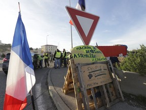 A group of demonstrators wearing their yellow vest occupy a traffic circle, Wednesday, Dec. 5, 2018 outside La Mede oil refinery, near Martigues, southeastern France. Trade unions and farmers pledged Wednesday to join nationwide protests against President Emmanuel Macron, as concessions by the government failed to stem the momentum of the most violent demonstrations France has seen in decades. On poster reads: Macron resigns, National Assembly dissolution. People suffering.