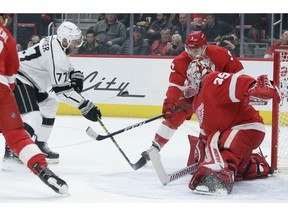 A shot by Los Angeles Kings center Jeff Carter (77) rebounds off of Detroit Red Wings goaltender Jimmy Howard (35) with Red Wings' Nick Jensen (3) helping defend the goal during the first period of an NHL hockey game Monday, Dec. 10, 2018, in Detroit.