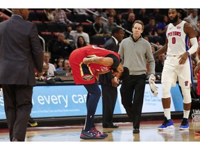 New Orleans Pelicans forward Anthony Davis, center, reacts after being injured in the first half of an NBA basketball game against the Detroit Pistons in Detroit, Sunday, Dec. 9, 2018.