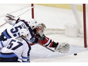 New Jersey Devils goaltender Keith Kinkaid, right, is unable to stop a shot by Winnipeg Jets center Mark Scheifele (55) during overtime of an NHL hockey game, Saturday, Dec. 1, 2018, in Newark, N.J.